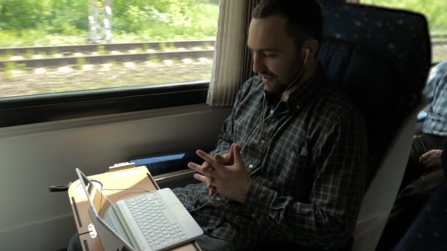 Man-chatting-with-his-laptop-in-a-train