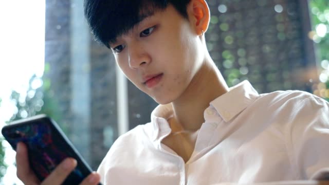 Joven-asiática-mirando-el-teléfono-inteligente-móvil