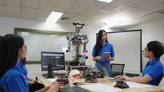 Asian-woman-engineer-present-robot-innovation-with-architects-design-team-in-laboratory.-Team-meeting-share-technology-ideas-and-collaborating-development-robot.-Concept-of-presentation-robotics-technology.