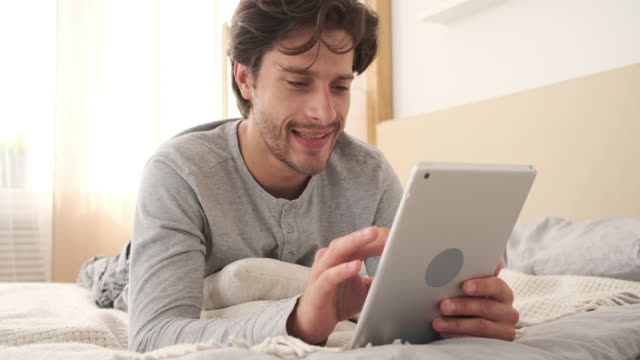 Mann-mit-digitalem-Tablet-im-Bett