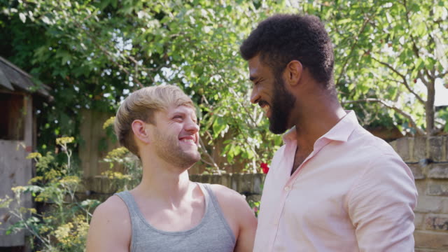 Porträt-von-liebenden-männlichen-Homosexuell-Paar-zu-Hause-im-Garten-gegen-flaring-Sonne-zusammen