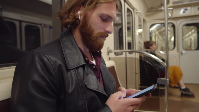 Mann-mit-Smartphone-im-U-Bahn-Auto-sitzen