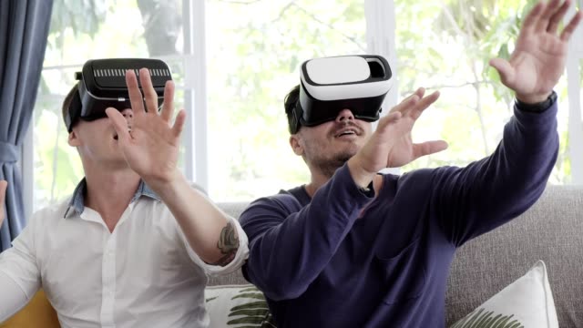 Gay-couple-relaxing-on-couch-using-virtual-reality-device.-Upward-shot.