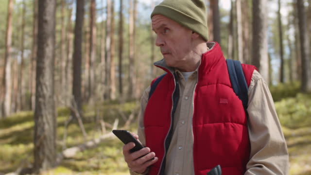 Sportliche-Senioren-mit-Telefon-im-Wald