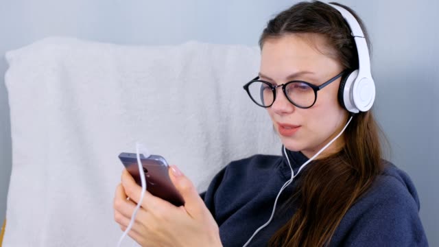 Woman-listens-music-in-headphones-on-smartphone-and-sings-a-song.