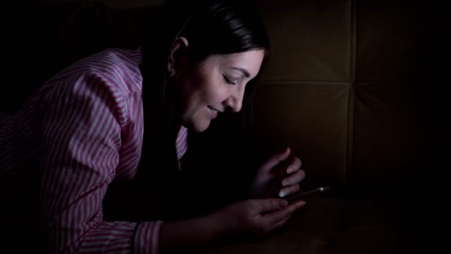 young-woman-leafing-through-a-social-network-feed-in-the-phone-at-night