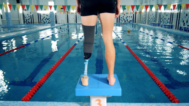 Schwimmbad-und-ein-Mann-mit-einem-Prothesenbein-stehend-auf-einem-Startblock