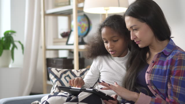 Mutter-und-brünette-Kind-sitzt-auf-dem-Sofa-und-verwendet-Wahl-digitale-Technologie