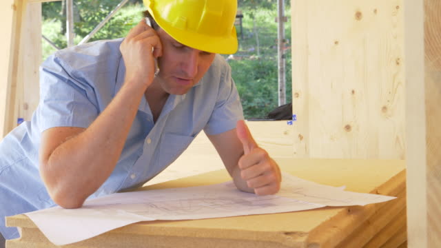 CLOSE-UP:-Architect-is-satisfied-as-he-talks-on-the-phone-about-the-floor-plans.