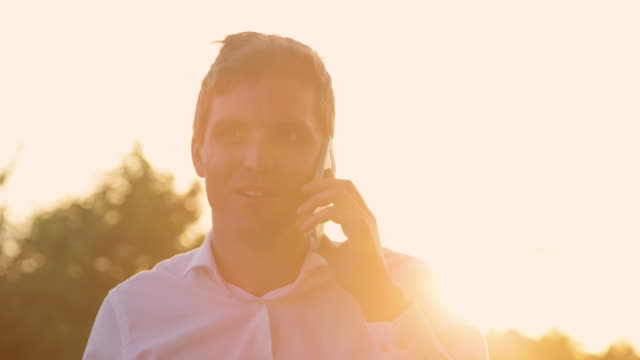 CLOSE-UP:-Man-cheerfully-talks-on-the-phone-on-sunny-evening-after-good-meeting.