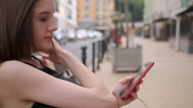Nettemädchen-verwenden-rote-Smartphone-im-Freien