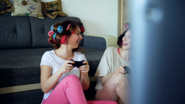 Two-funny-women-play-console-games-with-gamepad-and-have-fun-at-home