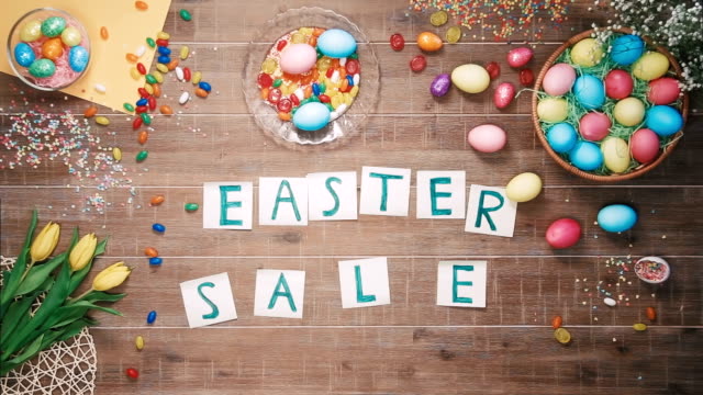 Man-puts-words-Easter-Sale-on-table-decorated-with-easter-eggs.-Top-view