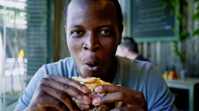 Happy-black-guy-laugh-and-eats-tasty-meat-burger