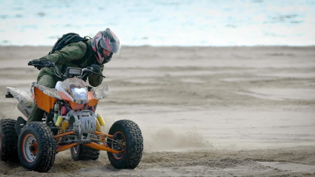 River-bank.-The-racer-works-the-movements-on-the-quad-bike.-The-man-on-the-ATV-studies-driving-at-sand
