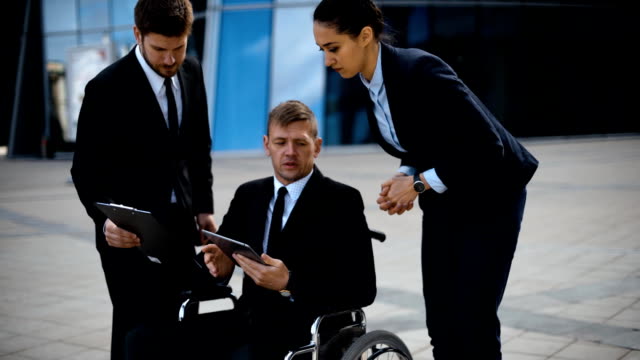 Young-disabled-businessman-talking-with-his-coworkers