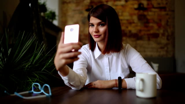 Casual-young-woman-talking-on-phone-having-conversation-via-video-chat-conference-at-home-office.-Businesswoman-using-smart-phone-app-on-smartphone-smiling-happy