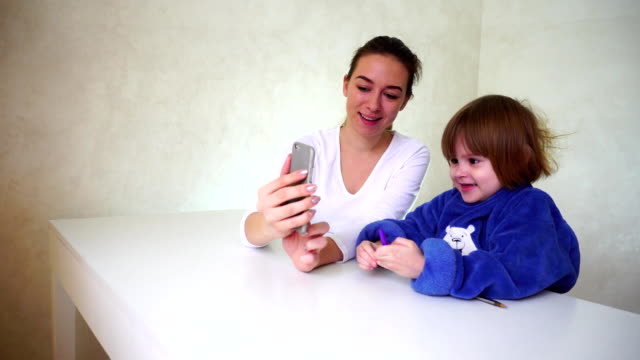 Junge-Mutter-und-Tochter-spielen-mit-Handy-Kamera,-Mädchen-sitzen-und-mit-lustigen-Kamera-Effekte
