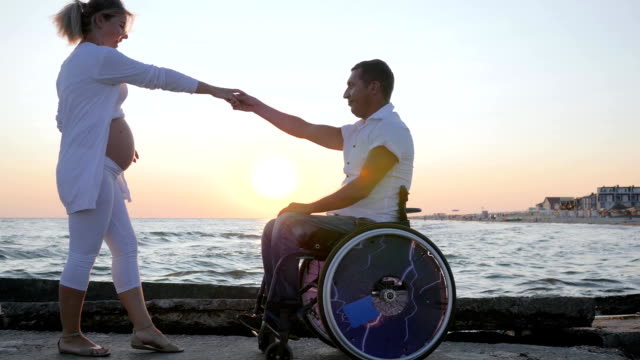 Menschen-mit-Behinderungen-und-Frau-tanzen-in-Abend-,-ungültige-Ehepartner-im-Rollstuhl-mit-trächtige-Weibchen-bei-Sonnenuntergang