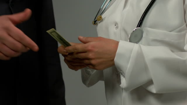 Businessman-giving-money-to-unfair-female-physician,-bribe-at-medical-center