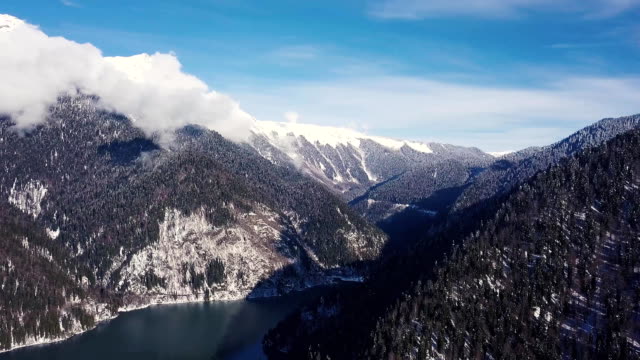Panoramische-Ansicht-der-schönen-weißen-Wunderland-Winterlandschaft-mit-schneebedeckten-Berggipfeln.-Clip.-Kristallklaren-Bergsee-an-einem-kalten,-sonnigen-Tag-mit-blauem-Himmel-und-Wolken