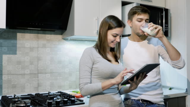 Glückliches-Paar-zu-Hause-in-Küche-Tablet-zusammen-mit