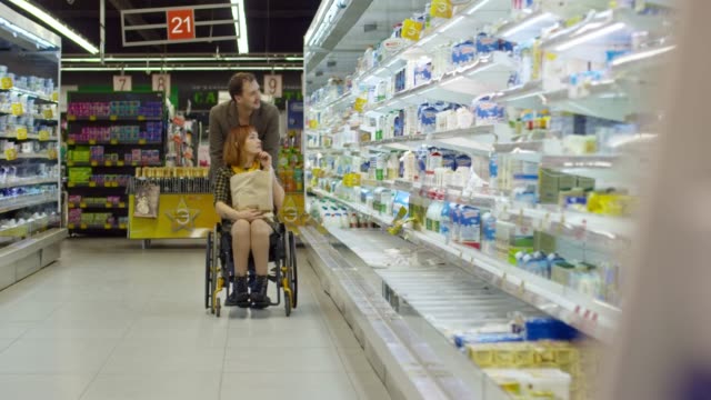 Parapléjico-mujer-elegir-leche-de-supermercado-con-marido