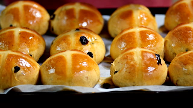 Homemade-Easter-traditional-hot-cross-buns.-Female-hands-cover-with-syrup