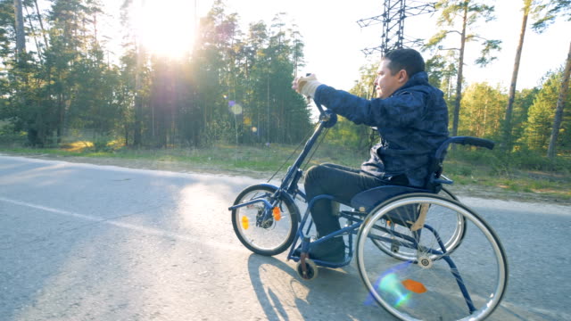 Disabled-person-rides-a-wheelchair-bicycle,-side-view.