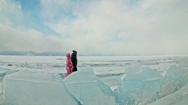 Junges-Paar-hat-Spaß-beim-Winterspaziergang-Hintergrund-von-Eis-der-zugefrorenen-See.-Liebhaber-Fuß-auf-dem-Eis,-einander-mit-der-hand-zu-halten,-küssen-und-umarmen.-Flitterwochen.-Liebesgeschichte.