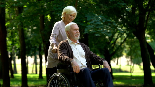 Fürsorgliche-Frau-unterstützt-ihren-Mann-im-Rollstuhl,-küssen-einander,-Familie