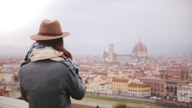 Happy-young-female-traveler-walks-up,-taking-smartphone-photo-of-amazing-cityscape-panorama-of-autumn-Florence,-Italy.