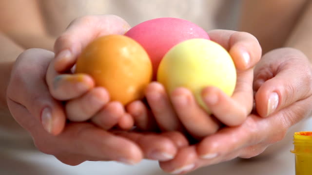 Mother-holding-daughters-hands-with-brightly-dyed-Easter-eggs,-family-traditions