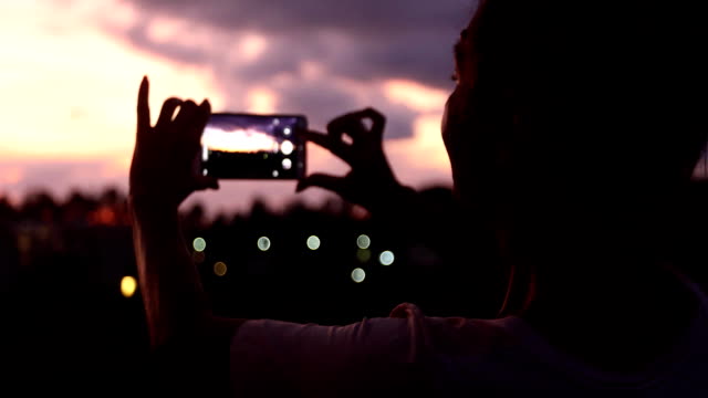 Frau-nehmen-Foto-mit-Sonnenuntergang-Himmel