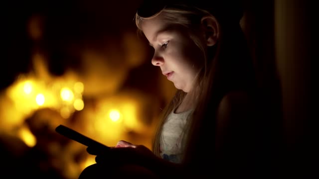 Niedliche-kleine-Mädchen-in-der-Nacht-nutzt-Smartphone-zu-Hause.-Mädchen-schreiben-Nachricht