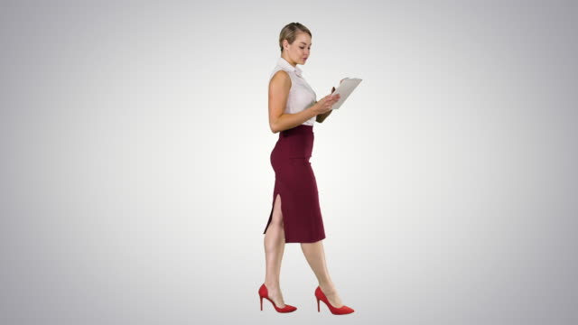 Businesswoman-using-electronic-tab-walking-on-gradient-background
