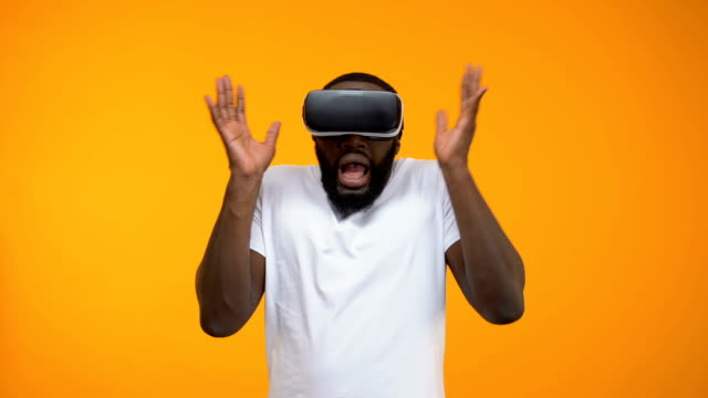 Scared-African-American-man-using-virtual-reality-headset,-simulation,-close-up