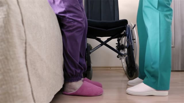 Krankenschwester-hilft-von-einer-behinderten-Seniorin-im-Rollstuhl