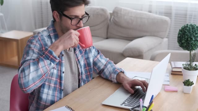 Hombre-de-negocios-bebiendo-café-mientras-trabajaba-en-el-ordenador-portátil