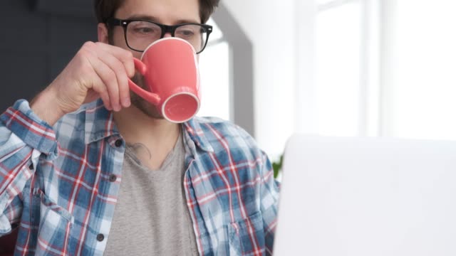 El-hombre-usando-el-ordenador-portátil-mientras-bebe-café