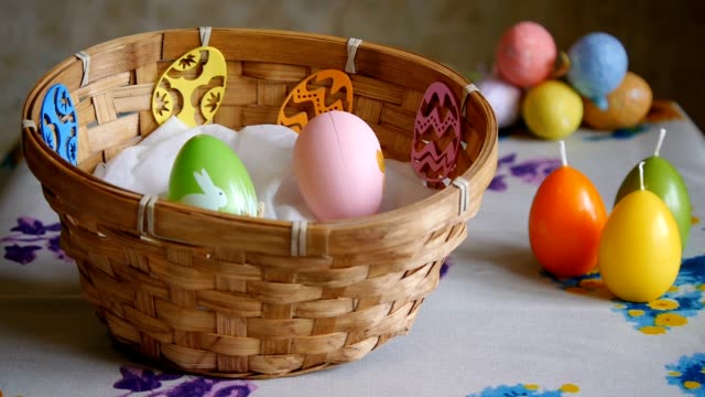 Coloridos-huevos-de-Pascua-verdes,-amarillos-y-rosados-en-una-cesta.-La-mano-masculina-añade-un-huevo-de-Pascua-rosado-y-uno-amarillo.