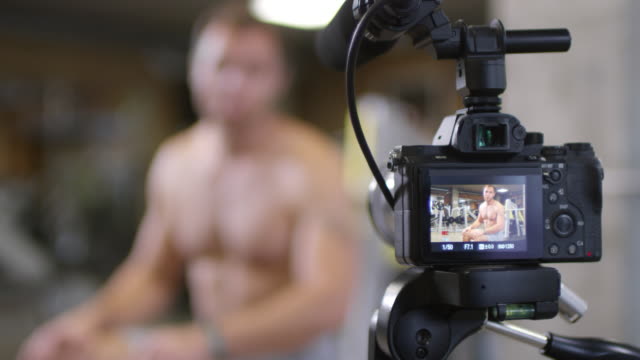 Entrenador-de-gimnasia-sin-camisa-mostrando-ejercicio-en-la-cámara