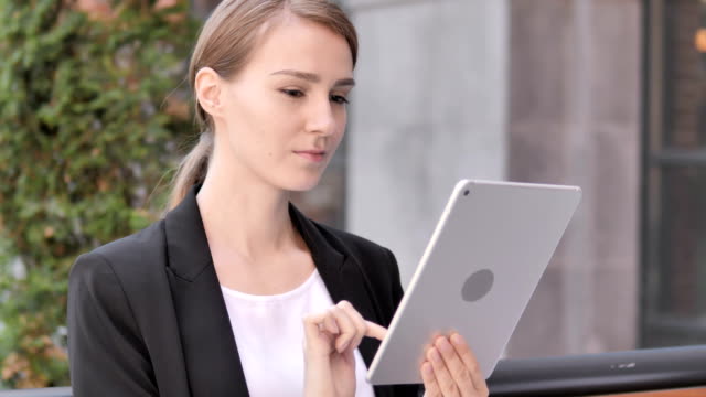 Joven-empresaria-sentada-al-aire-libre-y-usando-Tablet
