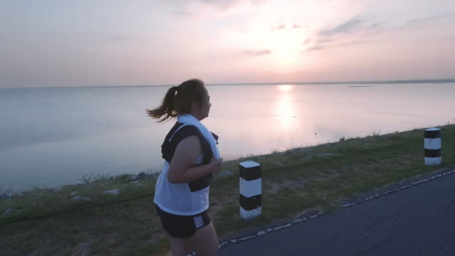 Asian-women-jogging-in-the-street-in-the-early-morning-sunlight-at-water-storage-Pa-Sak-Jolasid-Dam.-concept-of-losing-weight-with-exercise-for-health.-Slow-motion