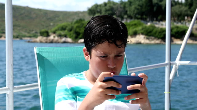 Young-boy-on-boat-using-smartphone