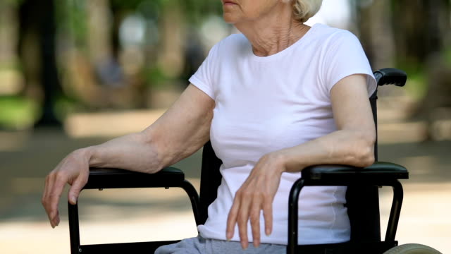 Mature-disabled-woman-crying-sitting-in-wheelchair-outdoor,-loneliness,-closeup