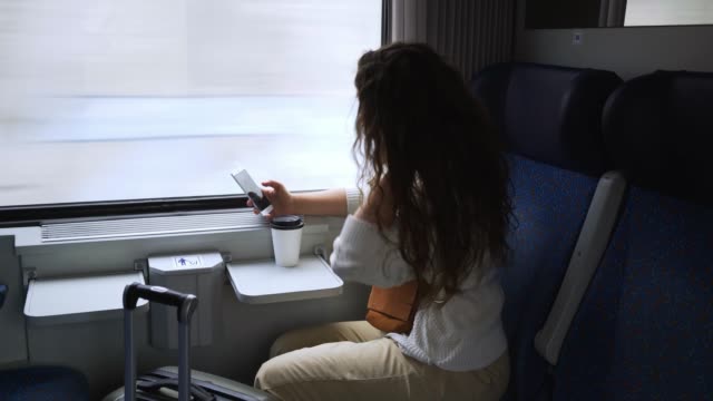 Unterwegs-auf-der-Zugfrau-mit-Telefon-in-der-Nähe-von-Fenster