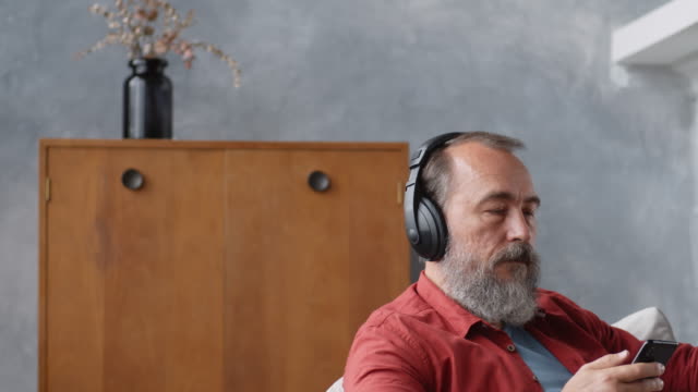 Retired-Man-Listening-to-Audio-Book-at-Home