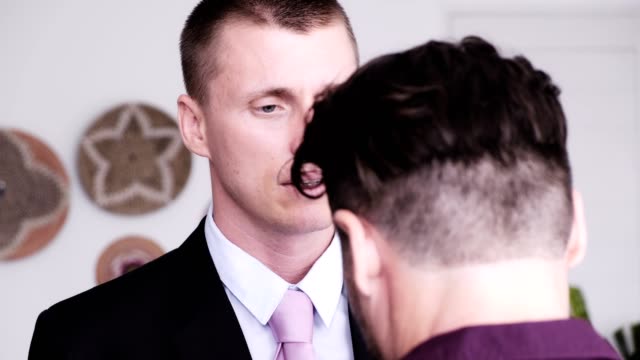 Hombre-gay-ayudar-a-su-pareja-a-poner-corbata-para-la-entrevista-de-trabajo.-Besando-adiós.