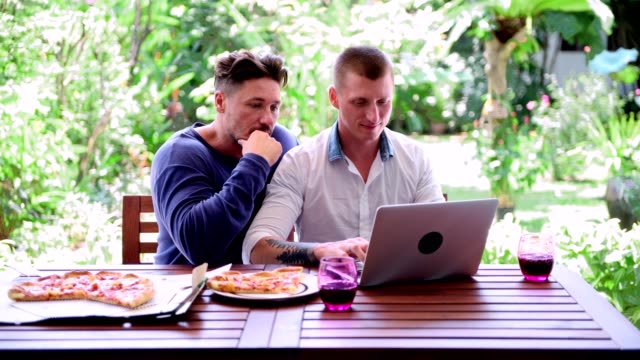 Gay-couple-having-pizza-for-lunch.-Drinking-wine.